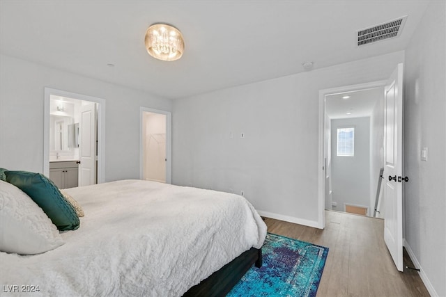 bedroom featuring hardwood / wood-style floors, ensuite bathroom, and a spacious closet