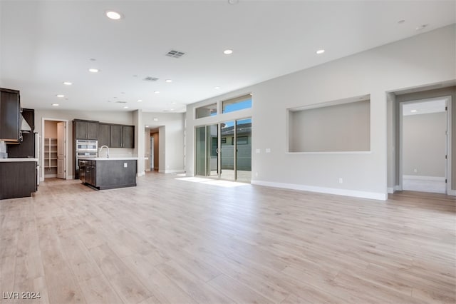 unfurnished living room with sink and light wood-type flooring