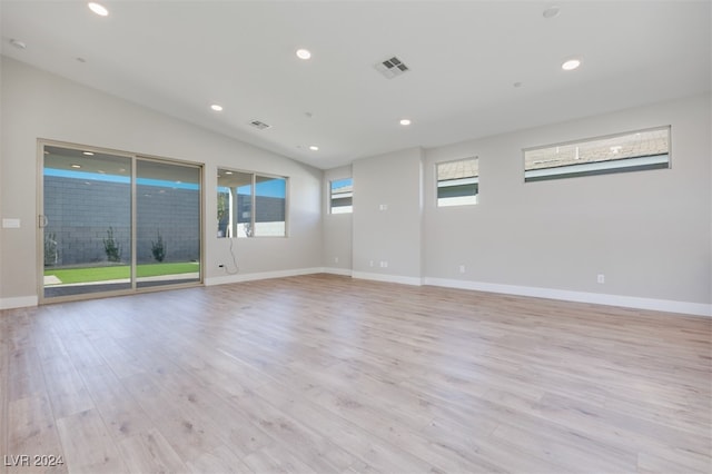 empty room with lofted ceiling, plenty of natural light, and light hardwood / wood-style flooring