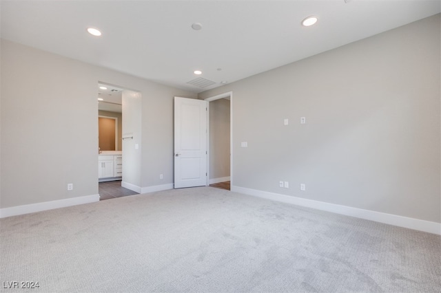 unfurnished bedroom featuring ensuite bath and dark colored carpet