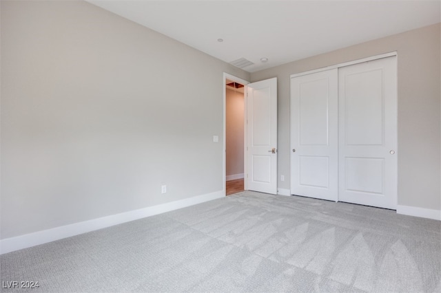 unfurnished bedroom featuring light carpet and a closet