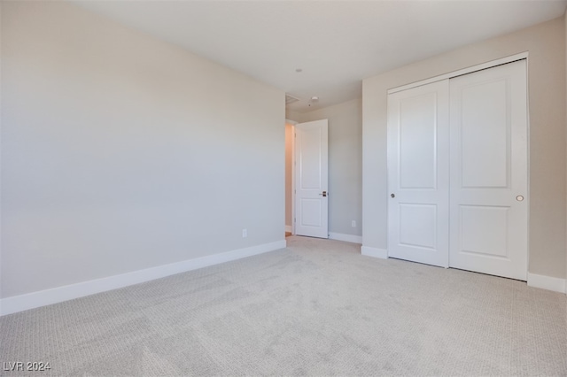 unfurnished bedroom with light colored carpet and a closet