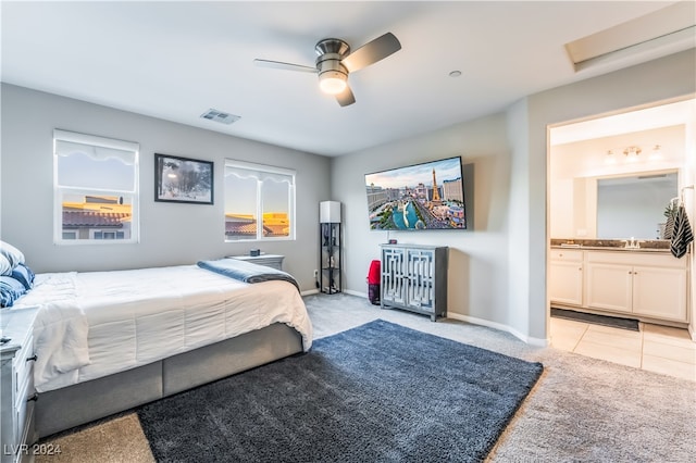 bedroom featuring light carpet, ensuite bathroom, ceiling fan, and sink