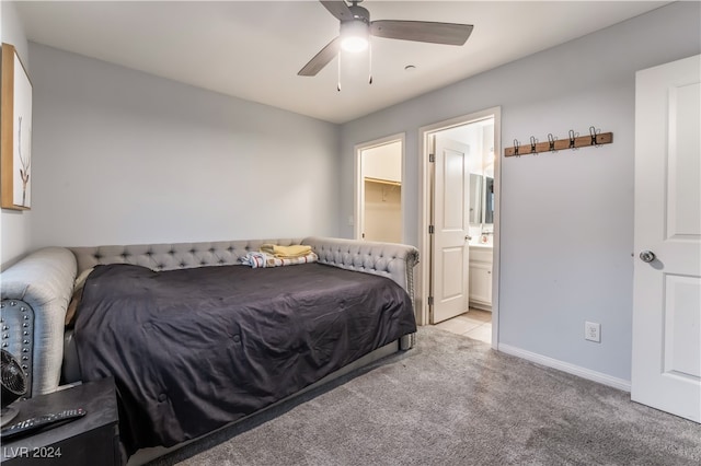 carpeted bedroom with ceiling fan, a spacious closet, and ensuite bath