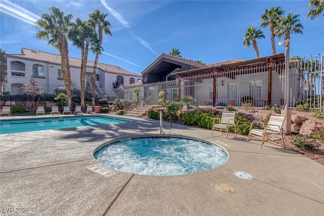 community pool featuring a patio area, fence, and a hot tub