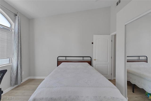 bedroom with light hardwood / wood-style floors and lofted ceiling