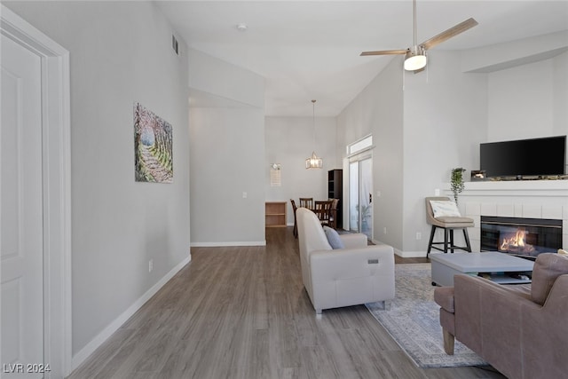 living room with a fireplace, ceiling fan with notable chandelier, and light wood-type flooring