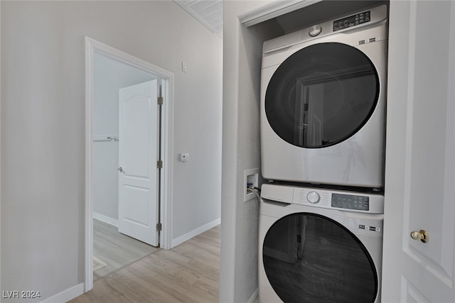 laundry room with light hardwood / wood-style floors and stacked washer / drying machine