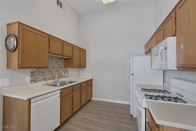 kitchen featuring decorative backsplash, white appliances, sink, and light hardwood / wood-style flooring