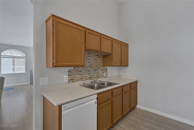 kitchen with tasteful backsplash, sink, white dishwasher, and light hardwood / wood-style flooring