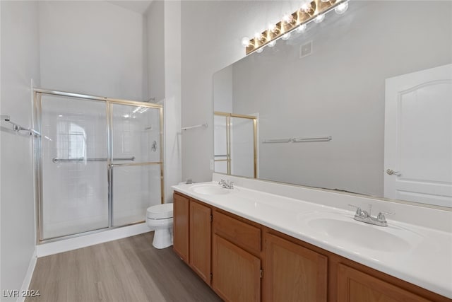 bathroom featuring vanity, toilet, wood-type flooring, and a shower with door