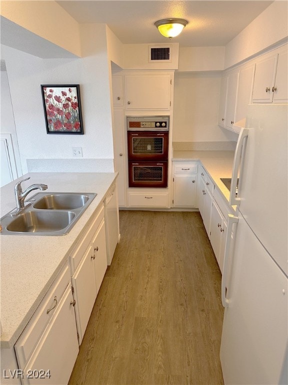 kitchen with white cabinets, white appliances, light hardwood / wood-style flooring, and sink