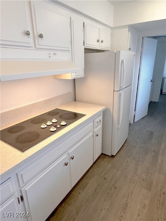 kitchen with white cabinets, white refrigerator, black electric cooktop, and light hardwood / wood-style flooring