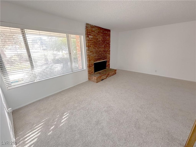 unfurnished living room with carpet, a textured ceiling, and a brick fireplace