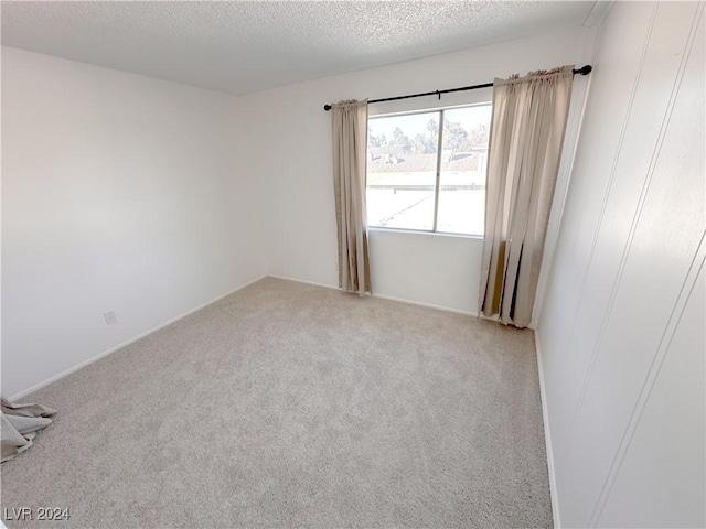 unfurnished room featuring a textured ceiling and light carpet