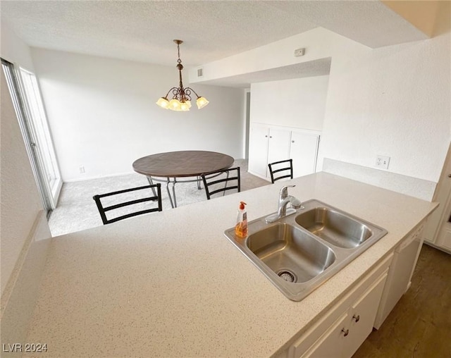 kitchen featuring white cabinetry, sink, a healthy amount of sunlight, a chandelier, and decorative light fixtures