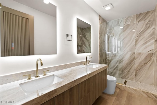 bathroom featuring vanity, toilet, hardwood / wood-style floors, and a tile shower