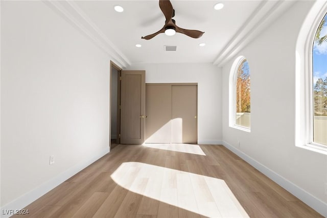 unfurnished bedroom with ceiling fan, light hardwood / wood-style floors, multiple windows, and a closet