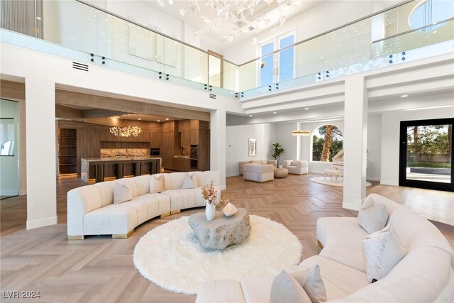 living room featuring a high ceiling, light parquet flooring, and a notable chandelier