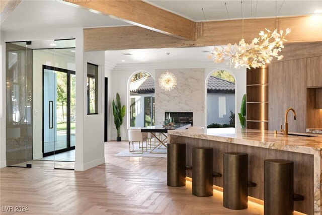 kitchen featuring pendant lighting, an inviting chandelier, light parquet floors, sink, and a premium fireplace