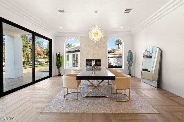 dining room with light parquet floors, crown molding, a notable chandelier, and a fireplace