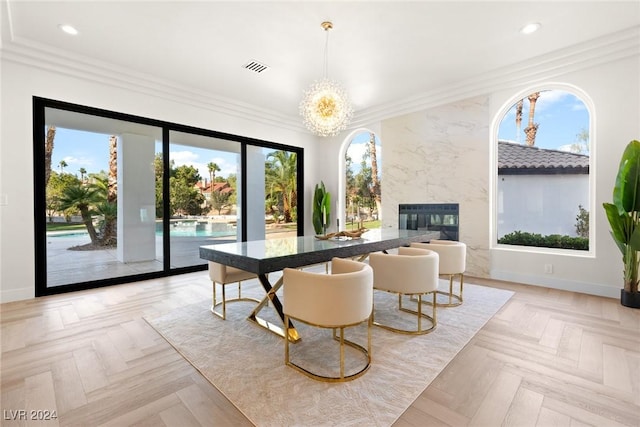 dining room with a fireplace, a chandelier, light parquet flooring, and ornamental molding