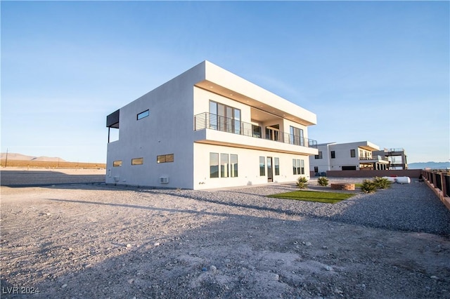 rear view of house featuring a balcony and stucco siding