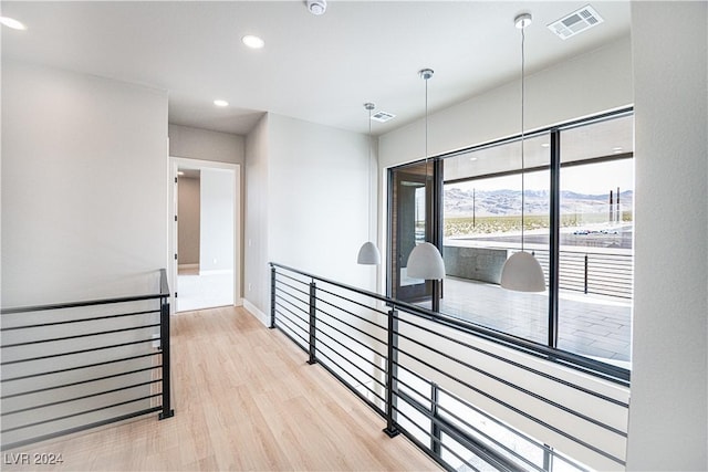 corridor featuring an upstairs landing, visible vents, and light wood-type flooring