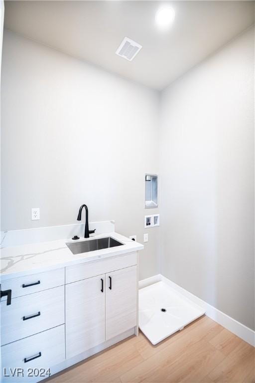 washroom featuring visible vents, hookup for a washing machine, a sink, light wood-style floors, and cabinet space