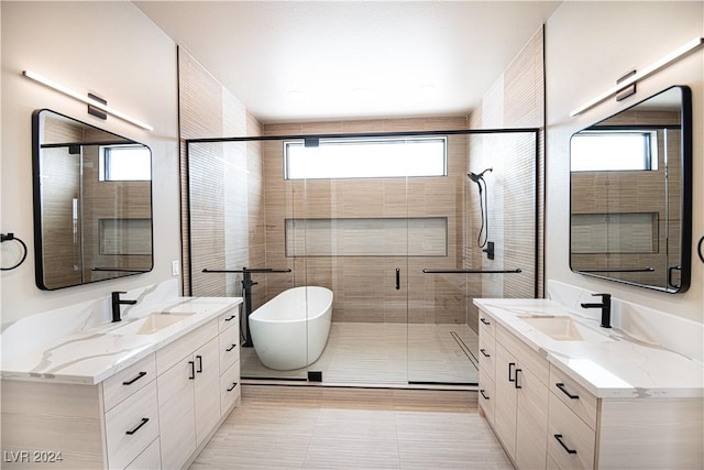 full bath featuring a sink, a soaking tub, two vanities, and a shower stall