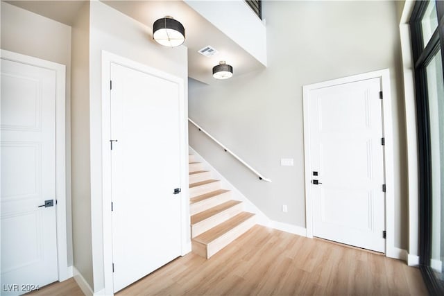 entryway with baseboards, visible vents, wood finished floors, and stairway