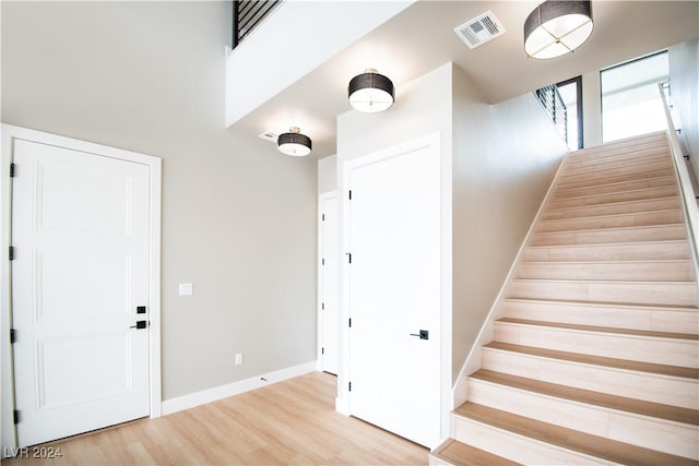 stairway featuring baseboards, visible vents, and wood finished floors