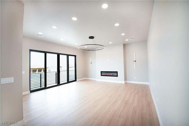 unfurnished living room featuring baseboards, light wood-type flooring, visible vents, and recessed lighting