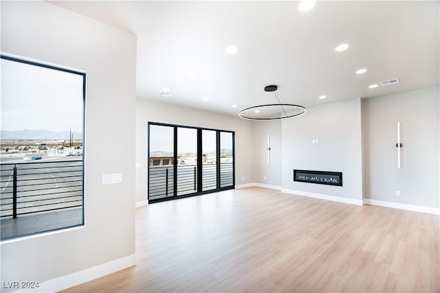 unfurnished living room featuring light wood finished floors, baseboards, visible vents, and recessed lighting