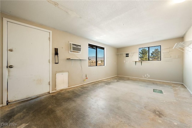 spare room featuring a wall mounted air conditioner, a wealth of natural light, and concrete floors