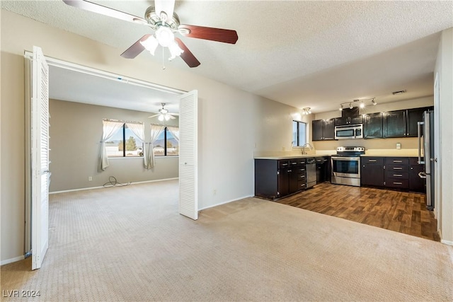 kitchen with appliances with stainless steel finishes, carpet flooring, sink, and a textured ceiling