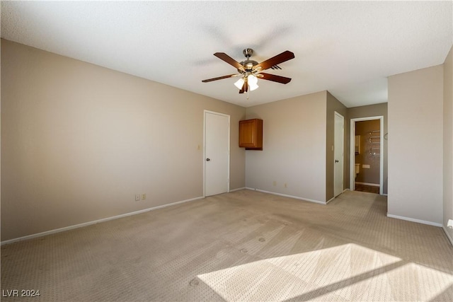 unfurnished bedroom with ceiling fan, connected bathroom, and light colored carpet