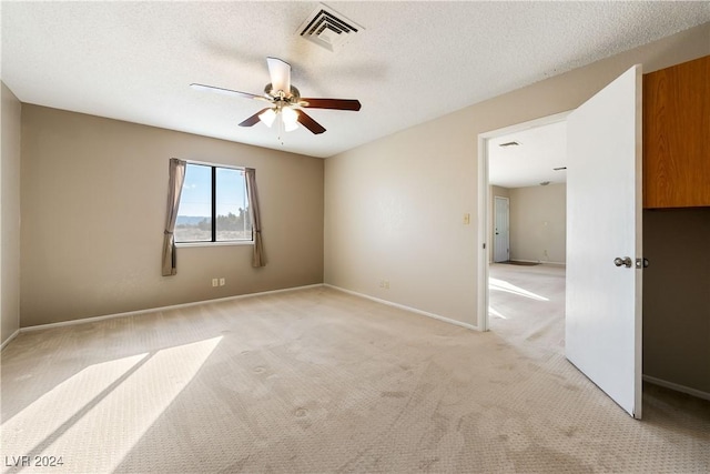 carpeted spare room with a textured ceiling and ceiling fan