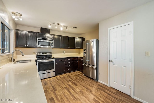 kitchen with appliances with stainless steel finishes, light hardwood / wood-style floors, and sink