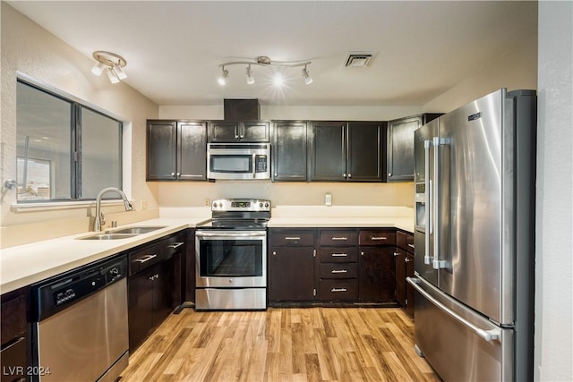 kitchen with dark brown cabinetry, stainless steel appliances, sink, and light wood-type flooring