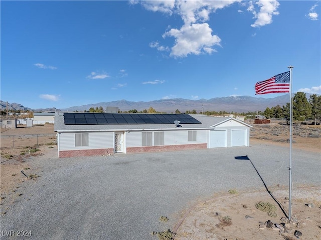 view of front of home with a garage, a mountain view, and solar panels