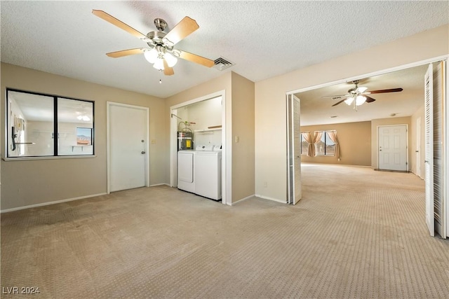 unfurnished room with ceiling fan, light carpet, washing machine and clothes dryer, and a textured ceiling