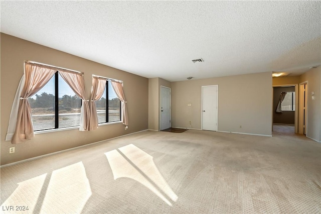 carpeted spare room featuring a textured ceiling and a water view