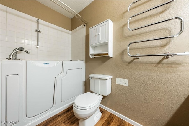 bathroom with hardwood / wood-style flooring, a textured ceiling, a tub, and toilet