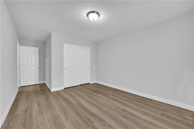 unfurnished bedroom with light hardwood / wood-style flooring and a closet