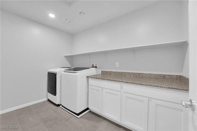 laundry area with washing machine and clothes dryer, light tile patterned floors, and cabinets