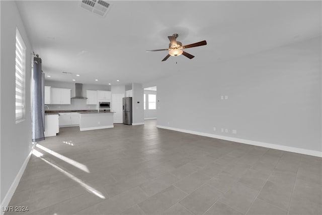 unfurnished living room featuring light tile patterned floors, a barn door, and ceiling fan