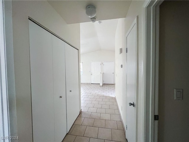 hallway featuring light tile patterned floors and vaulted ceiling