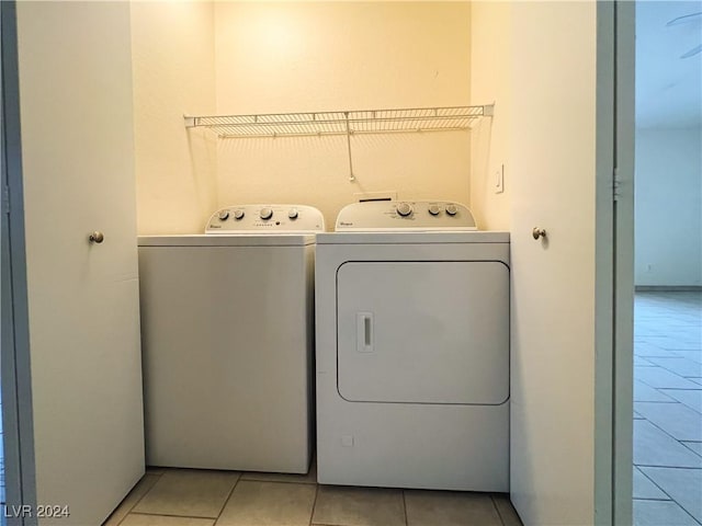 clothes washing area with washer and dryer and light tile patterned floors