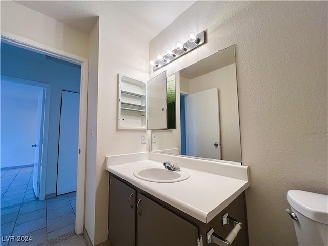 bathroom featuring vanity, tile patterned flooring, and toilet